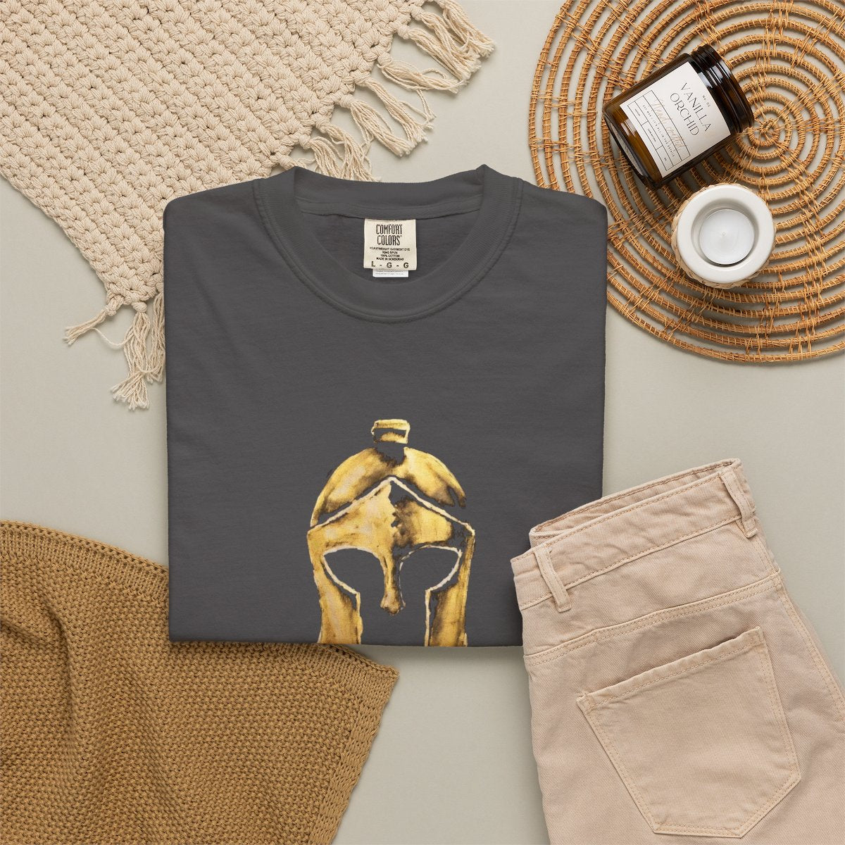 Graphite casual tee folded in a flat-lay, gold Helm helmet on the front