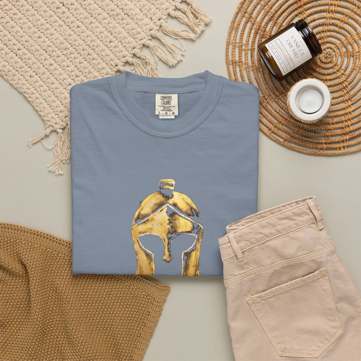 Blue Jean casual tee folded in a flat-lay, gold Helm helmet on the front