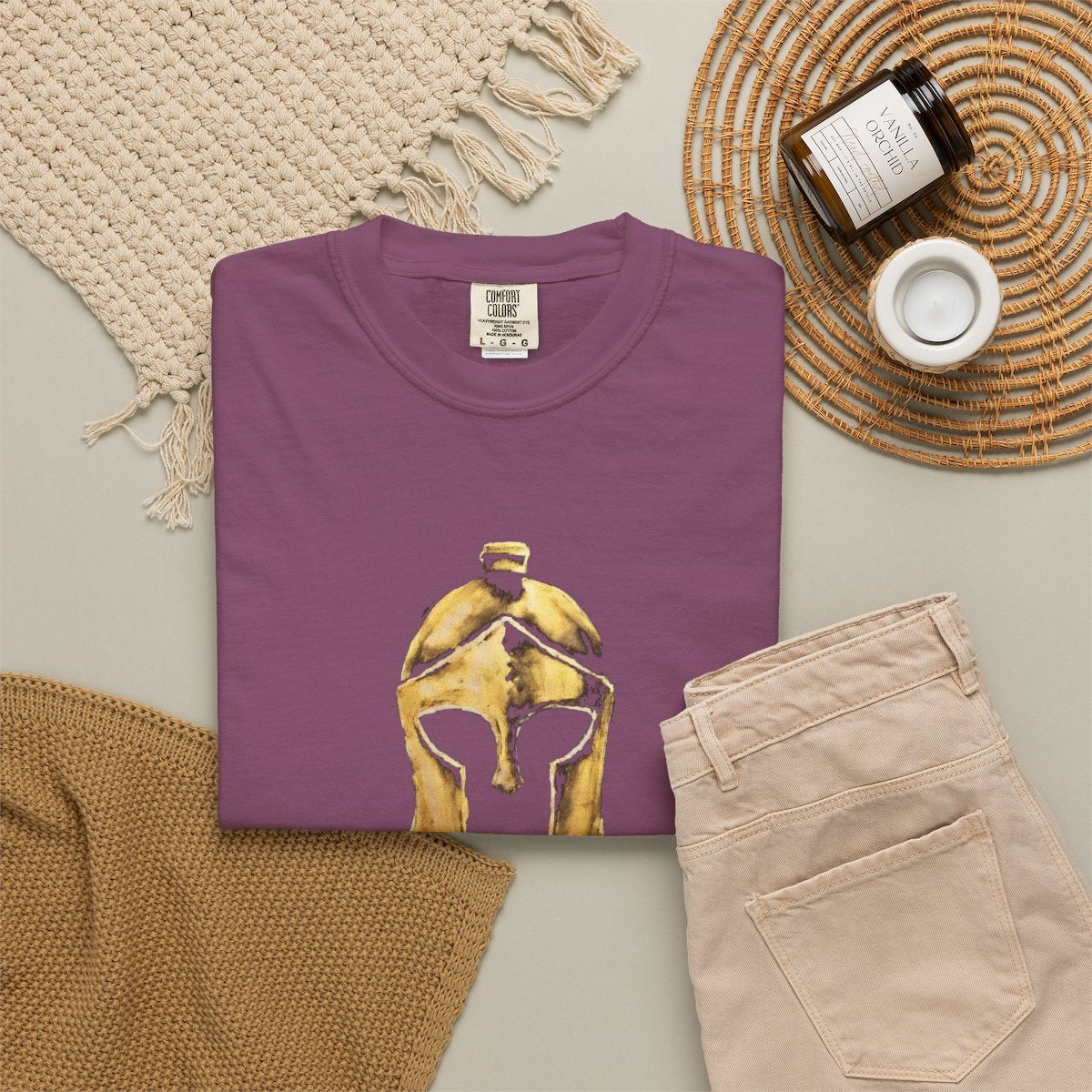 Berry casual tee folded in a flat-lay, gold Helm helmet on the front