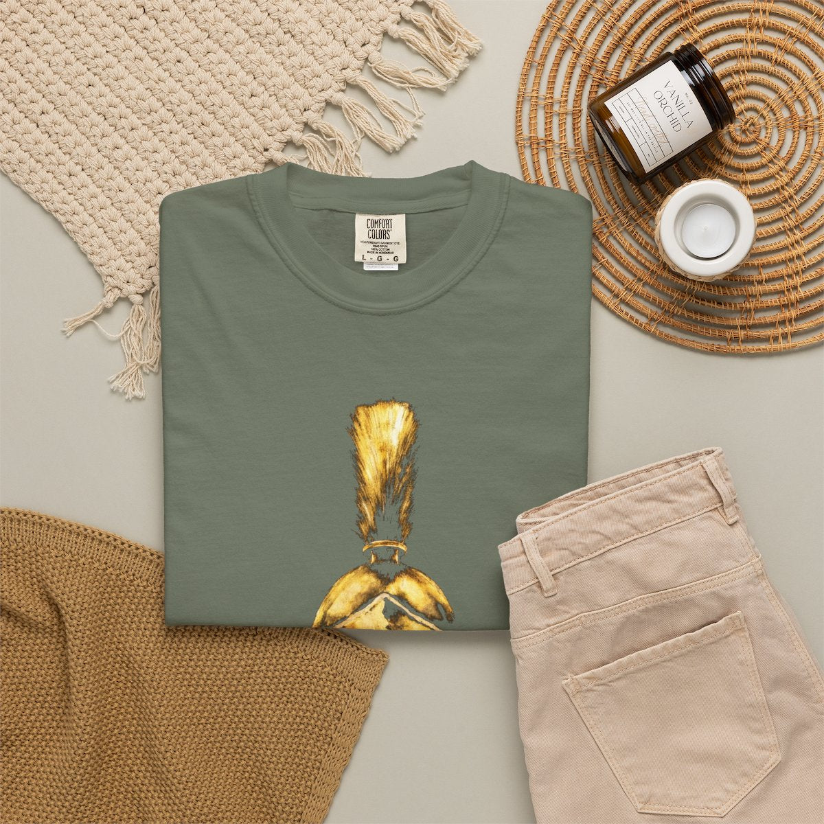 Moss casual tee folded in a flat-lay, gold Praetorian helmet on the front