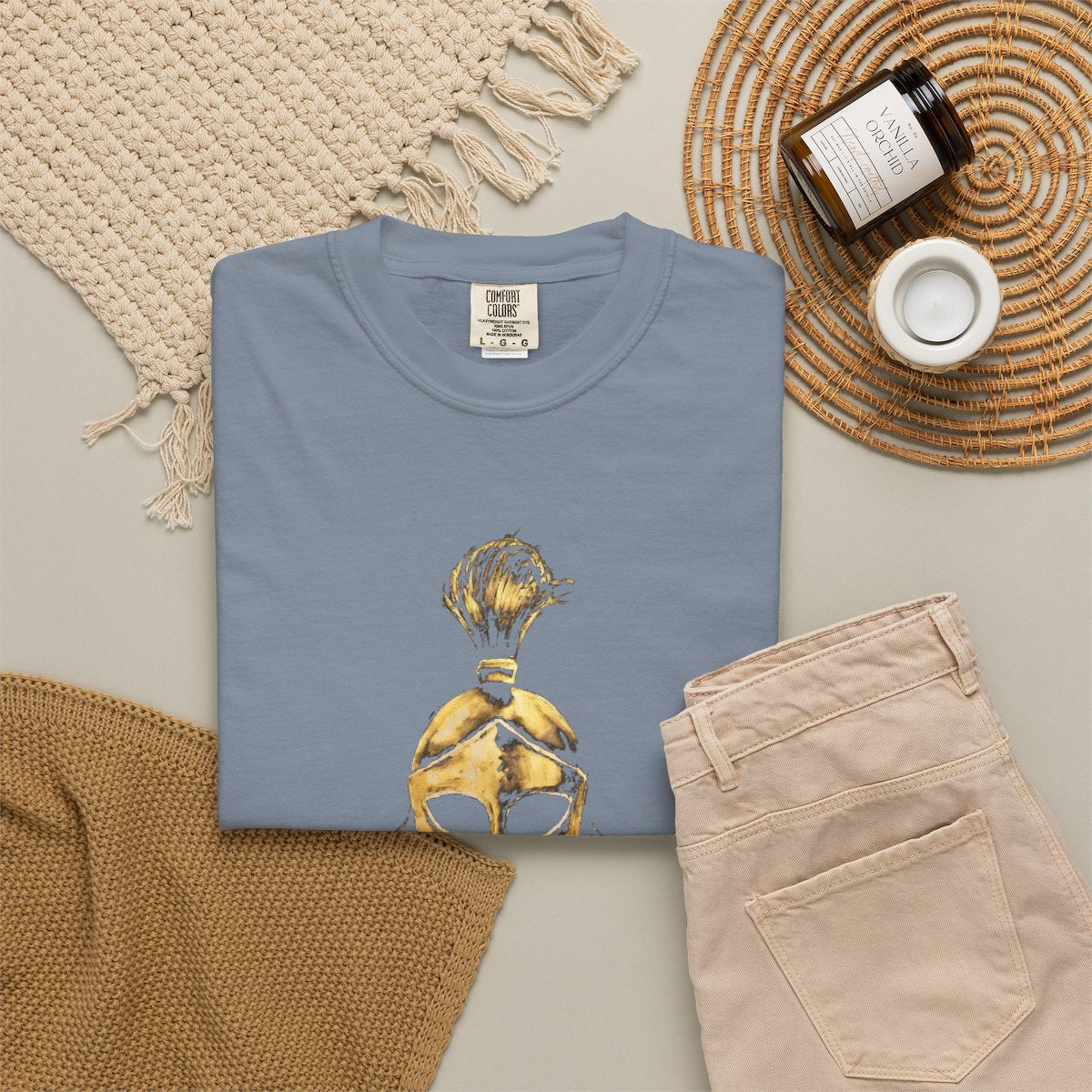 Blue Jean casual tee folded in a flat-lay, gold Sentinel helmet on the front