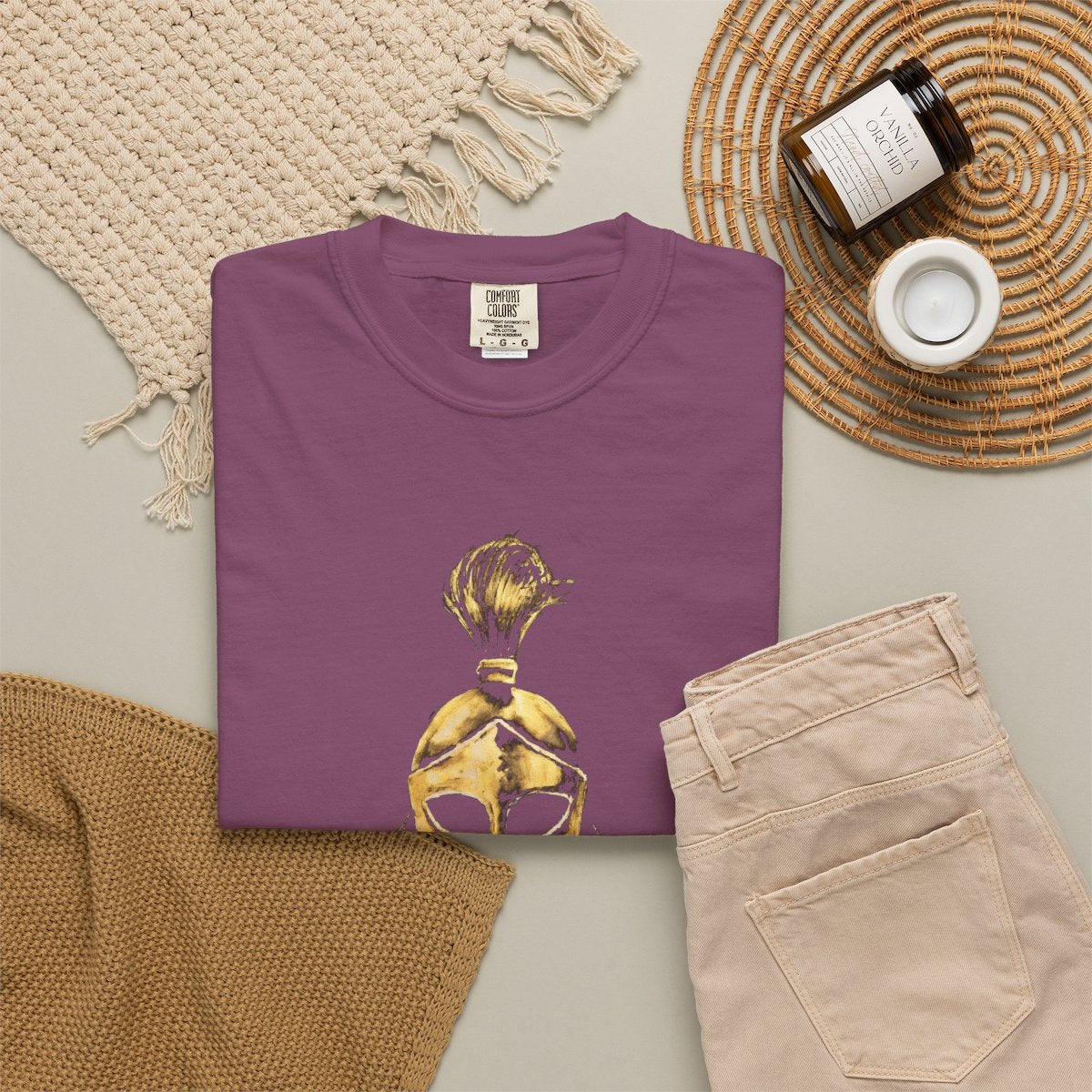 Berry casual tee folded in a flat-lay, gold Sentinel helmet on the front