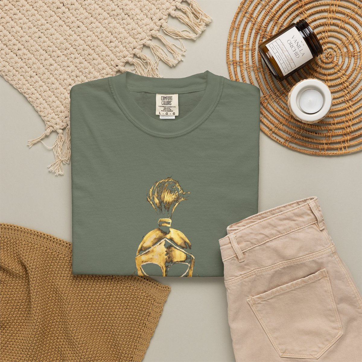 Moss casual tee folded in a flat-lay, gold Sentinel helmet on the front